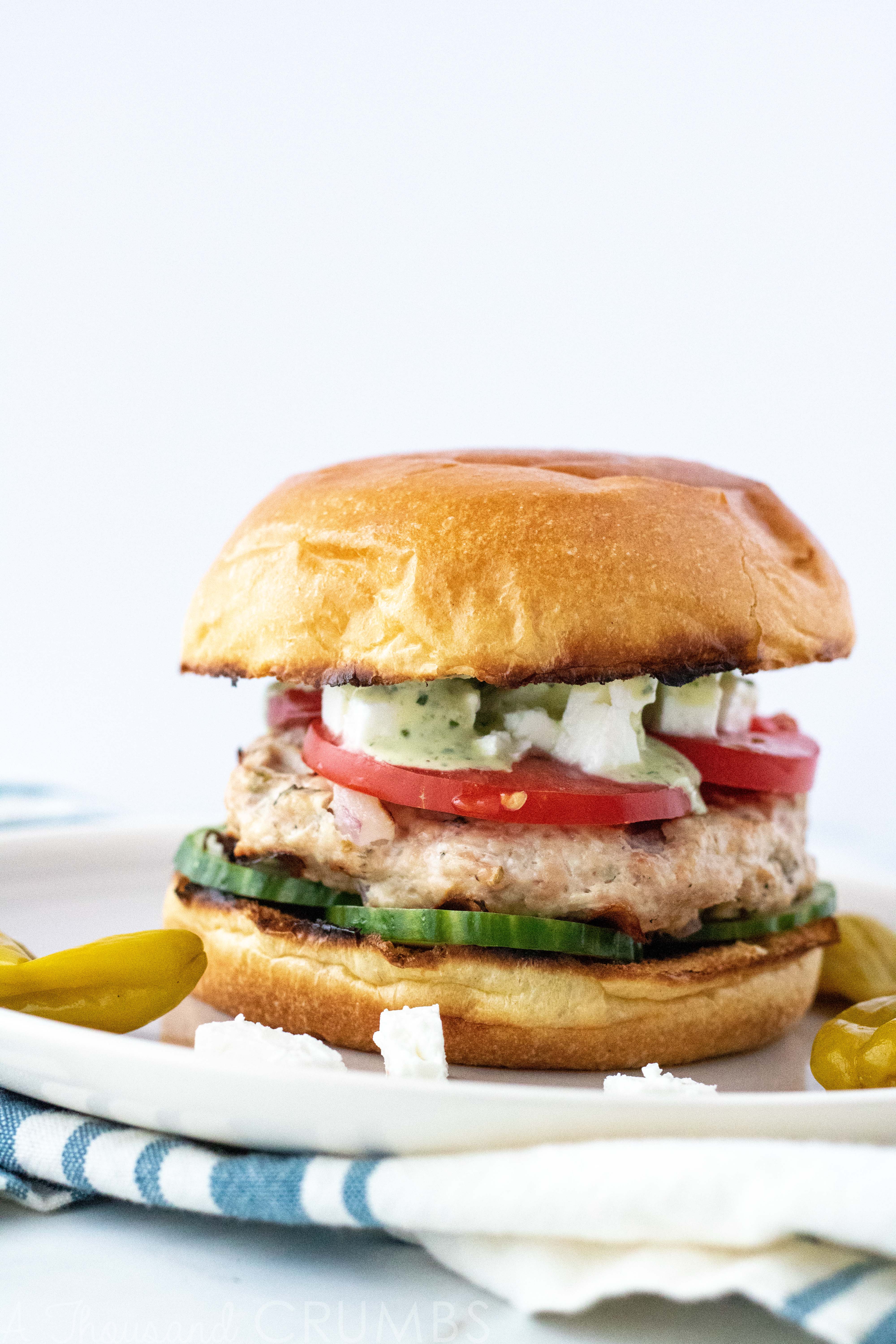 Greek Chicken Burgers full of flavor, and so easy to make! #athousandcrumbs #greekfood #chickenburgers #healthydinner #dinnerrecipe #burgerrecipe